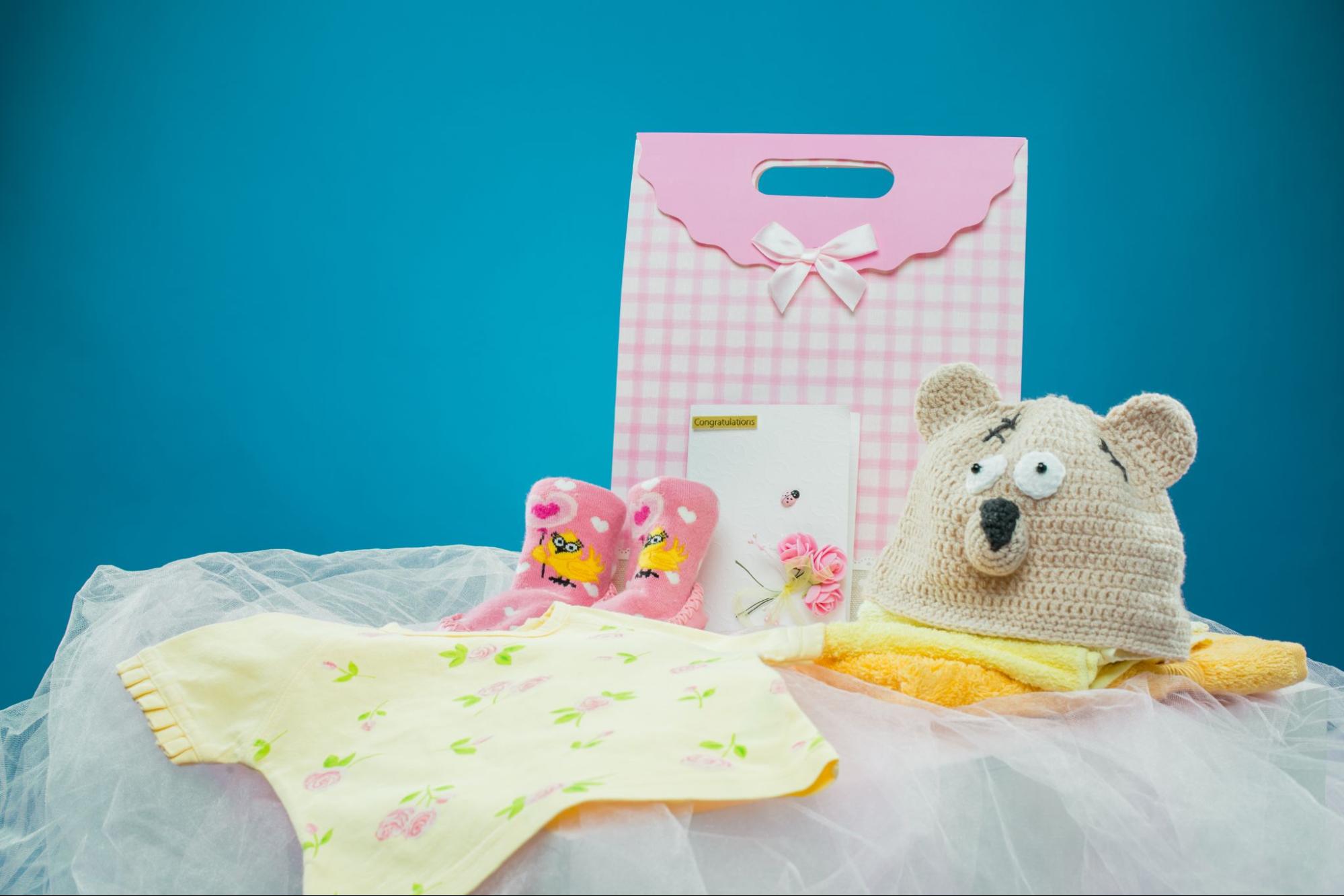 Baby shower gifts with a plush toy, pink booties, and a yellow onesie