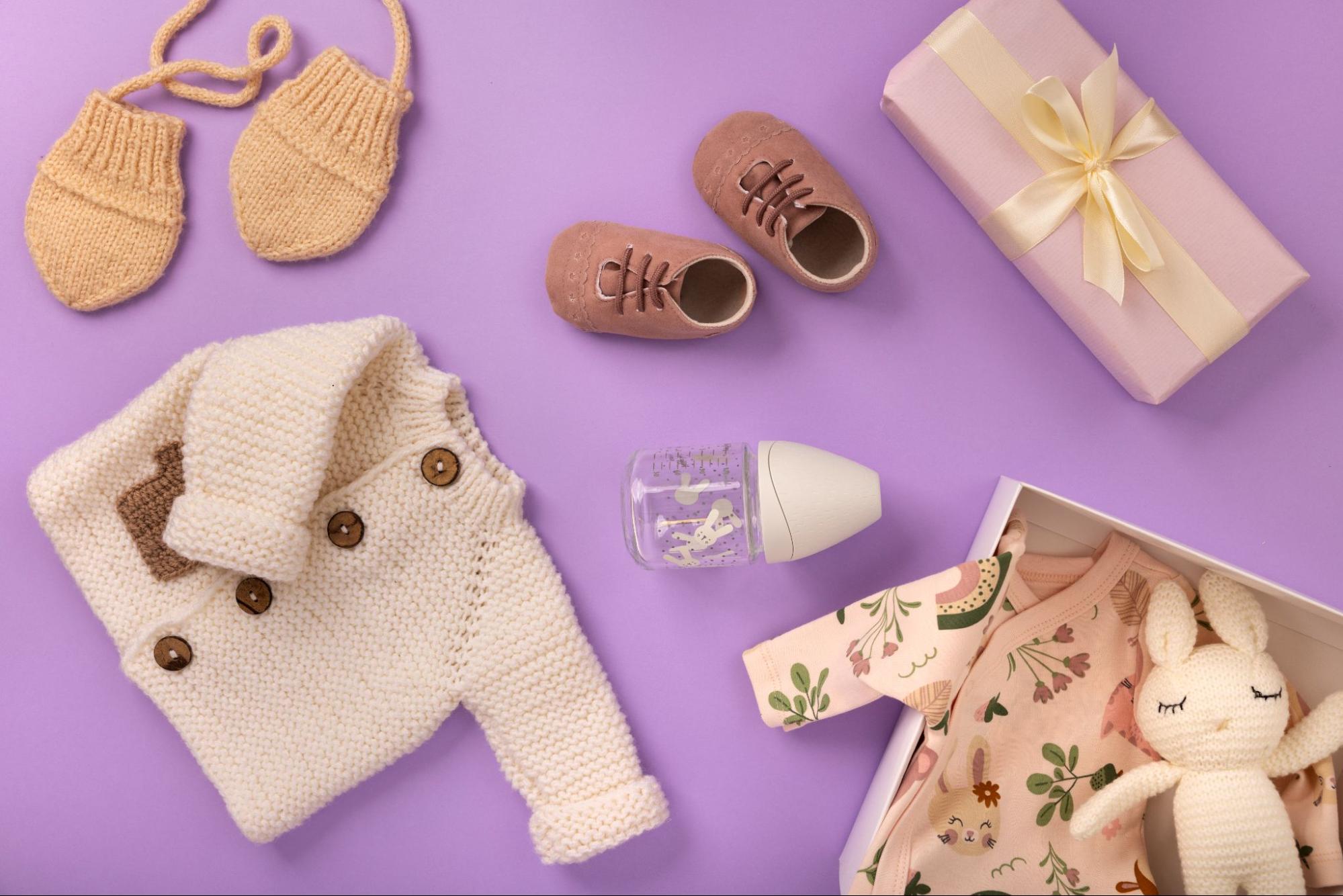 Baby knitwear and gifts on purple background, baby shower ideas.