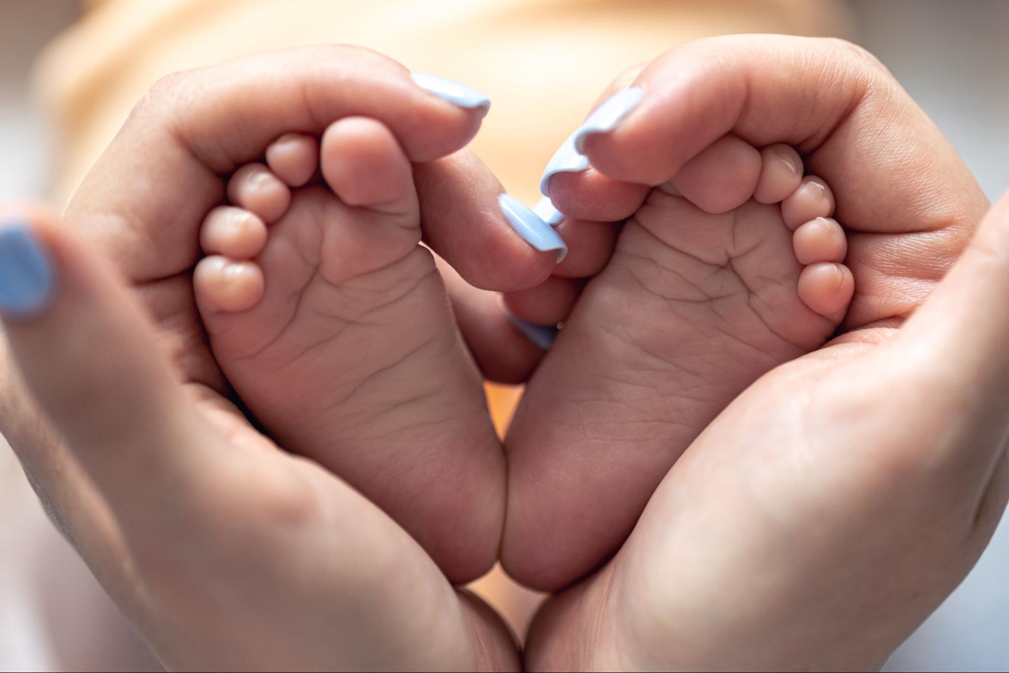 Tiny baby feet cradled in hands, a sweet baby shower gift idea for a keepsake