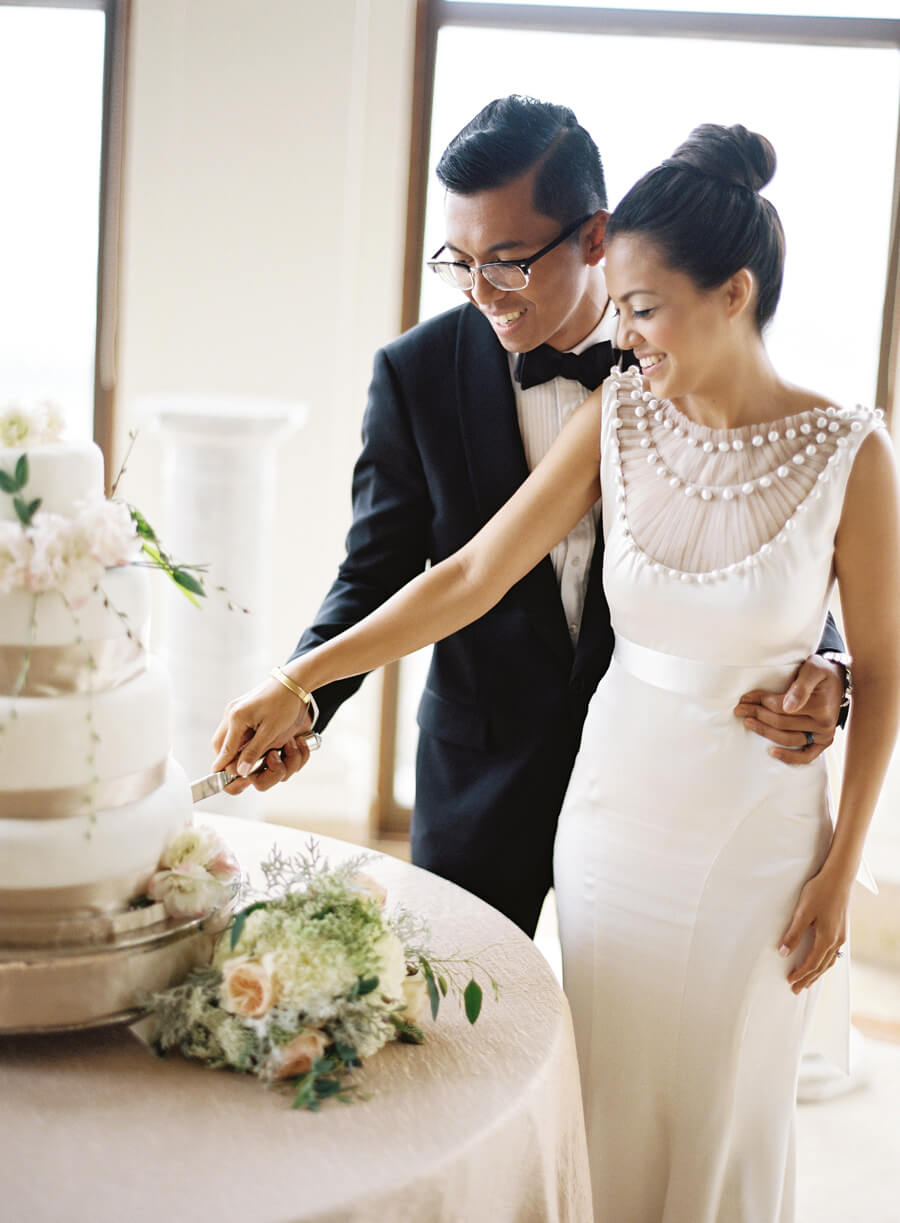 Bride and groom cutting a wedding cake pose