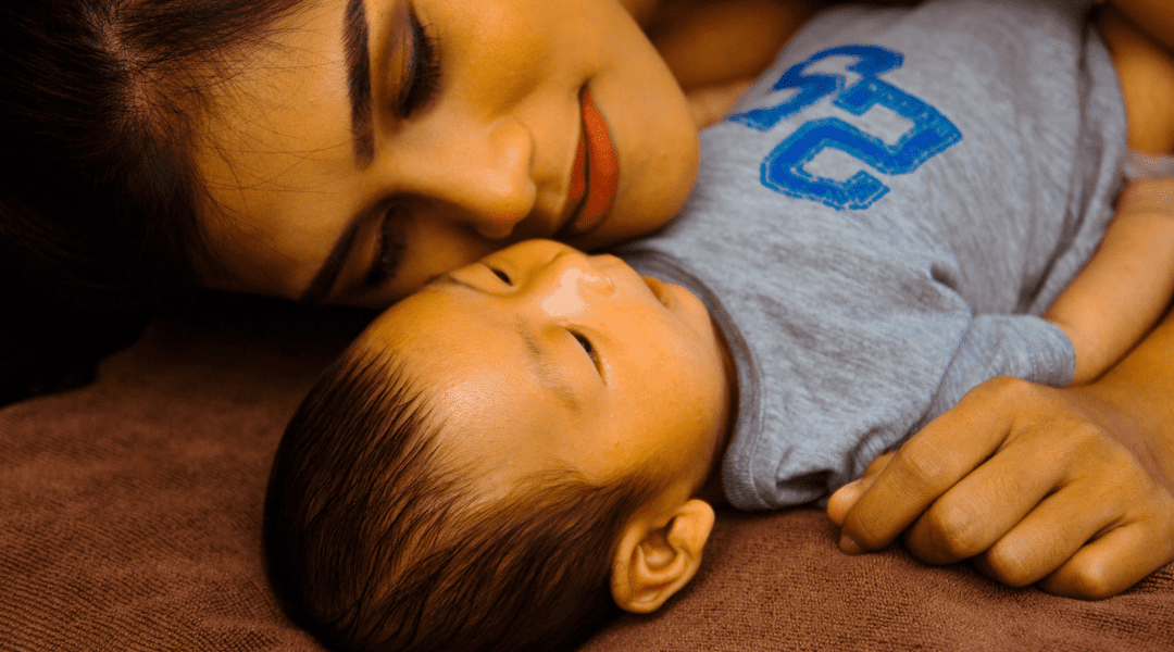 Mommy looking at the baby lying beside her.