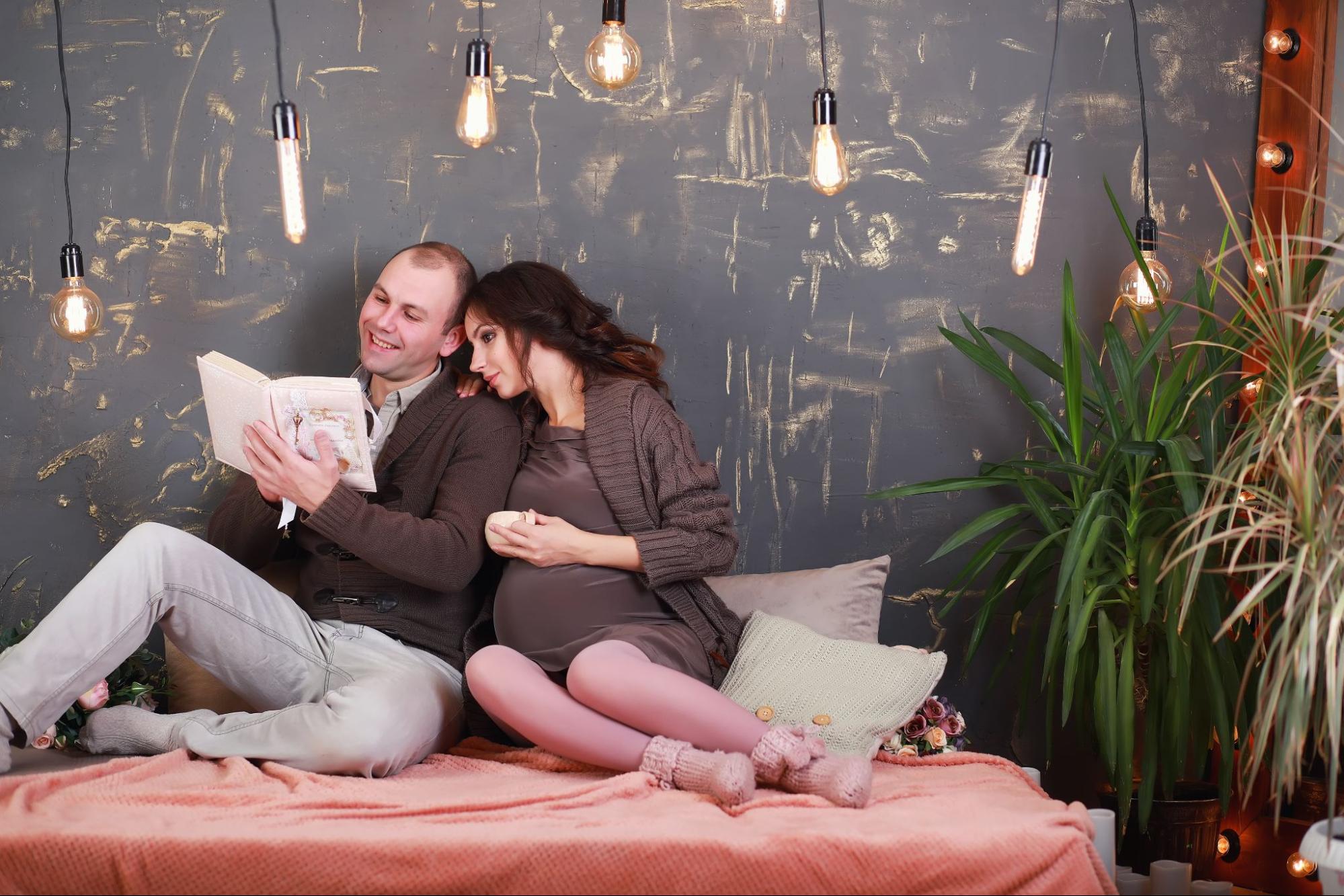 Indian couple posing for maternity baby shoot. The couple is posing in a  lawn with green