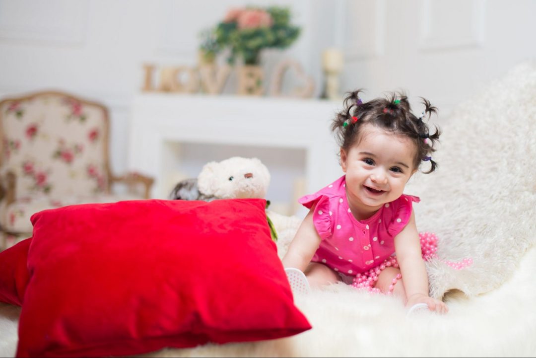 Colorful toys surrounding cute 6-month baby for at-home photoshoot