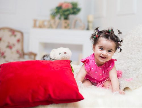 Colorful toys surrounding cute 6-month baby for at-home photoshoot