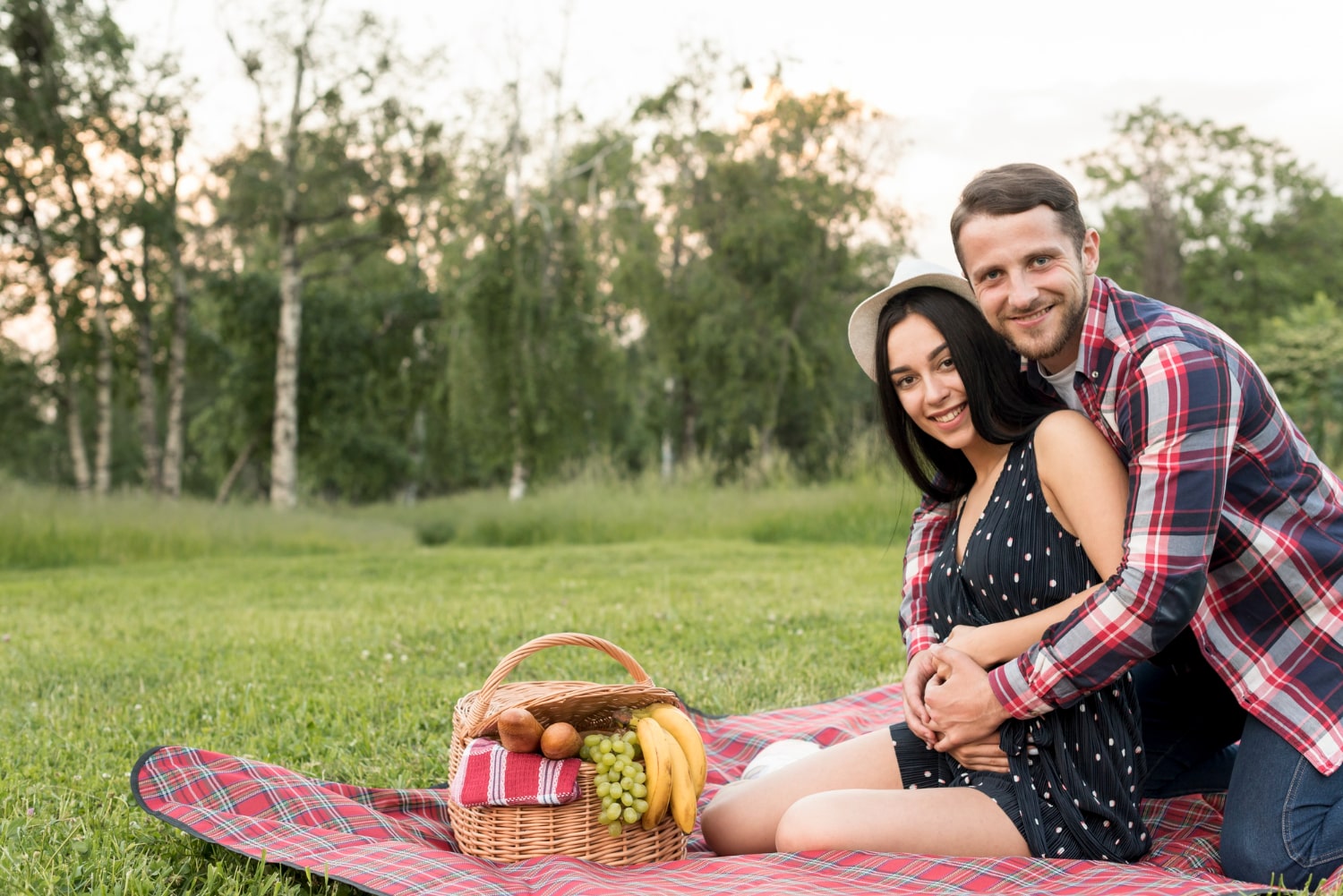 Couple enjoying a romantic picnic on a blanket in the grass. Perfect anniversary gift idea for couples.