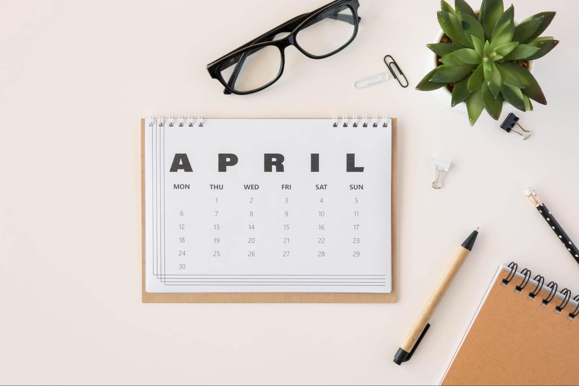 April desk calendar with pen, glasses, plant: 'Unplugging for Well-Being: Reducing Screen Time